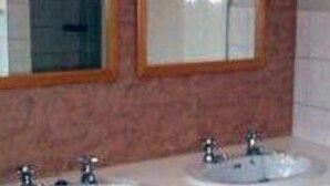 A bathroom with two sinks and two mirrors with wooden frames. - Hayesthorpe Hotel (South Croydon)