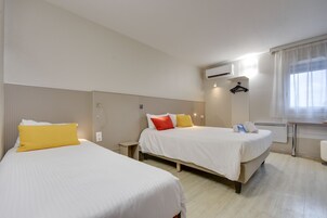 Habitación de hotel con dos camas, una mesita de noche, un espejo y una ventana con cortinas.