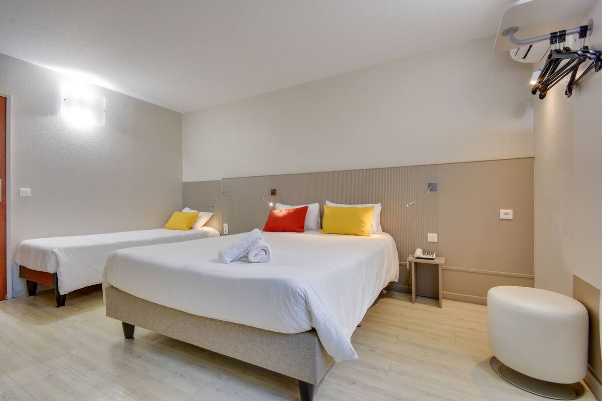 A hotel room with two beds, a bedside table, a lamp, and a wall-mounted bike rack.