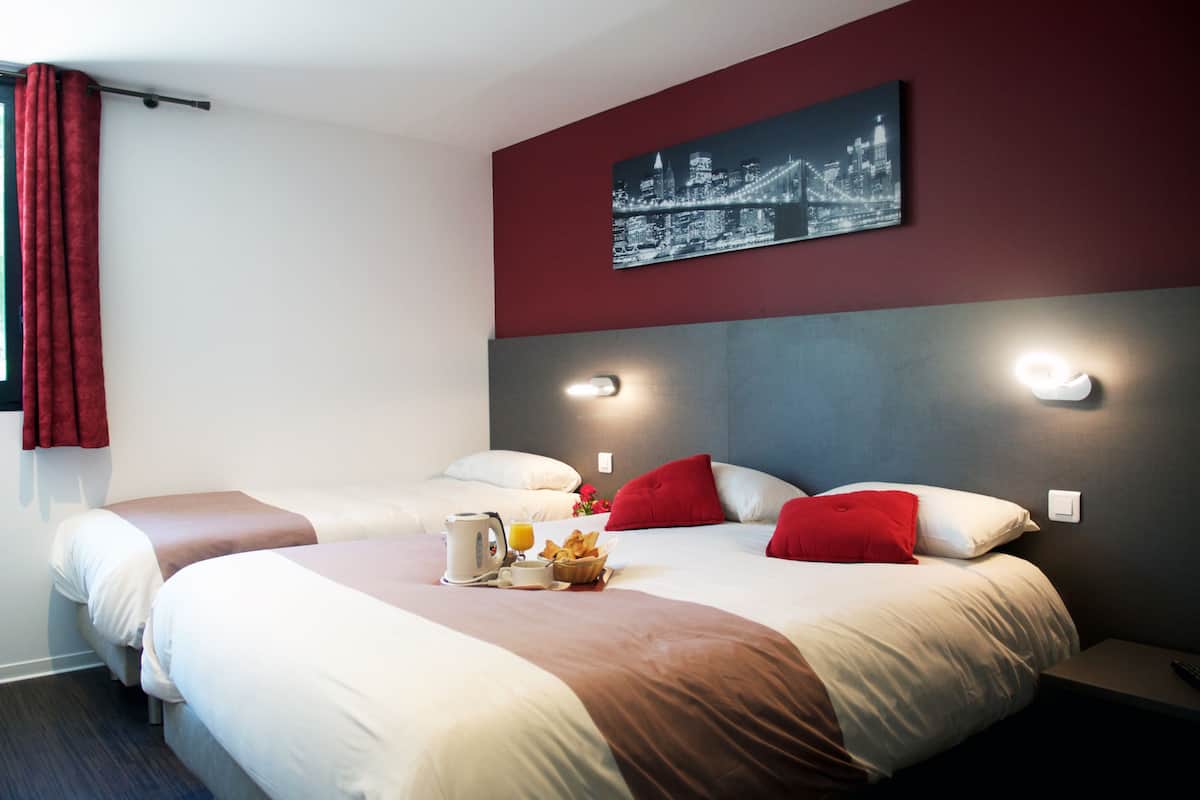 Ein Hotelzimmer mit zwei Betten, einem Stadtbild an der Wand und einem Frühstücksbrettchen auf dem Bett.