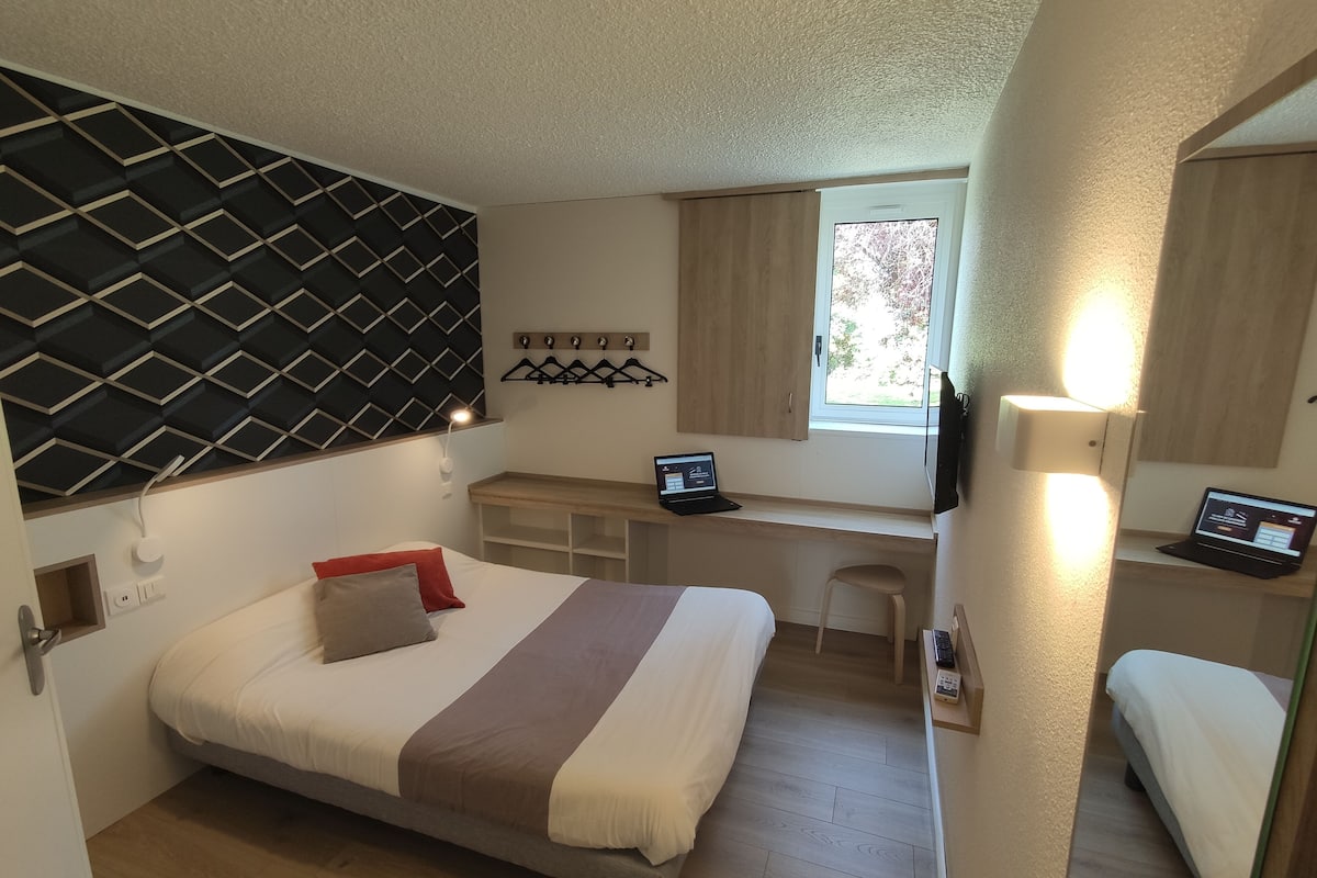 Ein gemütliches Schlafzimmer mit Bett, Schreibtisch und Laptop.