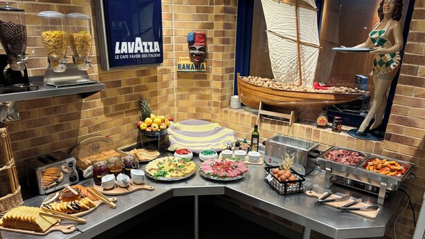A buffet setup with various food items and a decorative ship model. - Le Voltaire (Rennes)