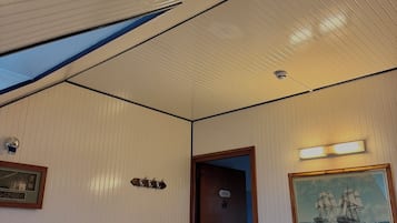 A hotel room with a bed, a painting, a door, and a phone.