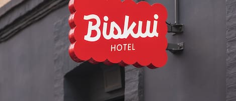 Un letrero de hotel con el nombre 'Biskui Hotel' y un logotipo de 'B' en rojo.