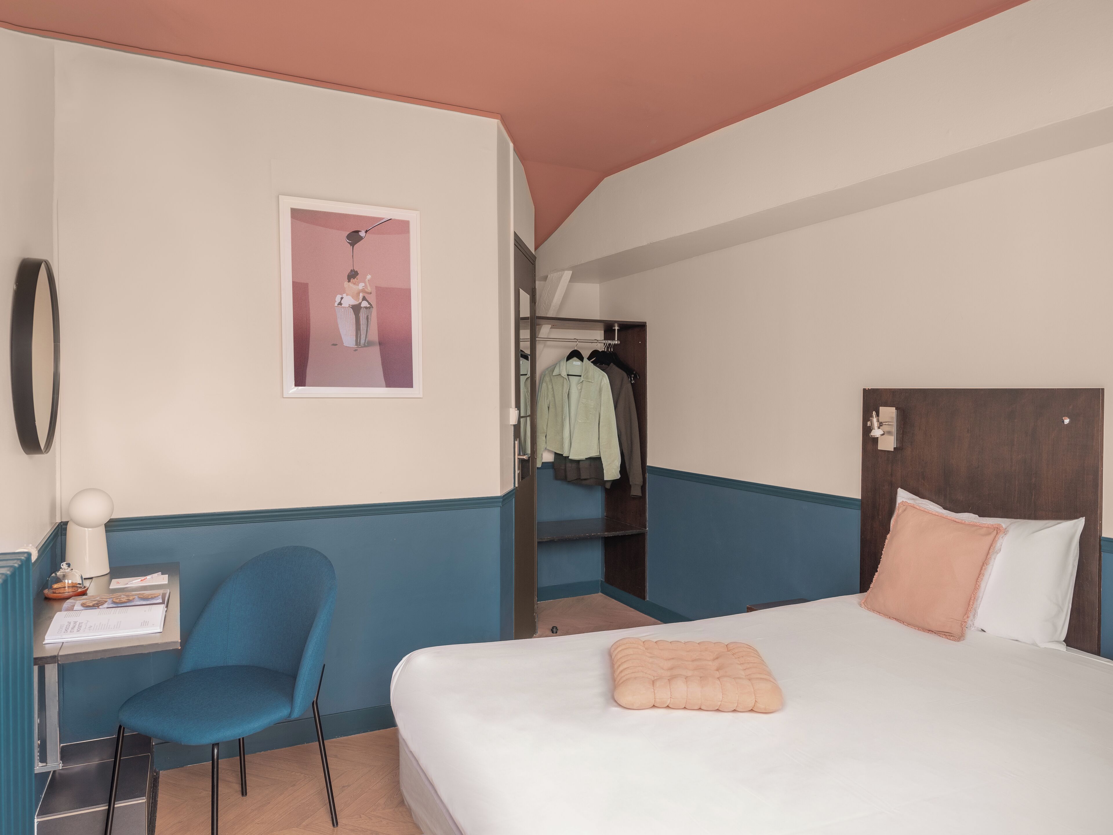 A hotel room with a bed, a chair, a desk, and a wardrobe.