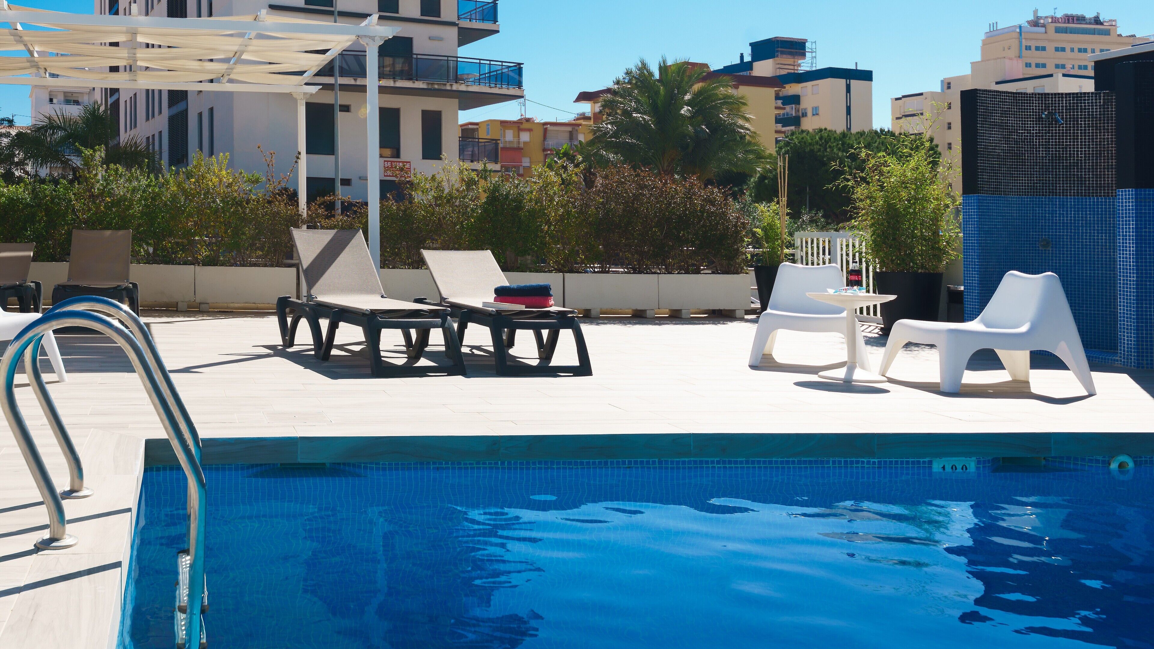 Un espace piscine sur le toit, avec des chaises longues et une piscine.