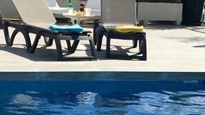 A swimming pool with lounge chairs and a table with drinks. - Hotel Albatros (Gandia)