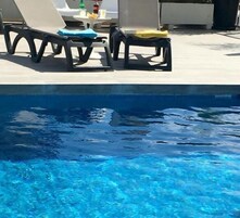 Una piscina al aire libre, sombrillas, tumbonas