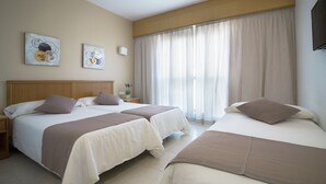 A hotel room with two beds, a wooden headboard, a nightstand, and a window with curtains. - Hotel Albatros (Gandia)