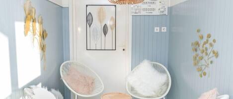 Una habitación con sillas de mimbre blancas, una mesita redonda pequeña y un tapete tejido.
