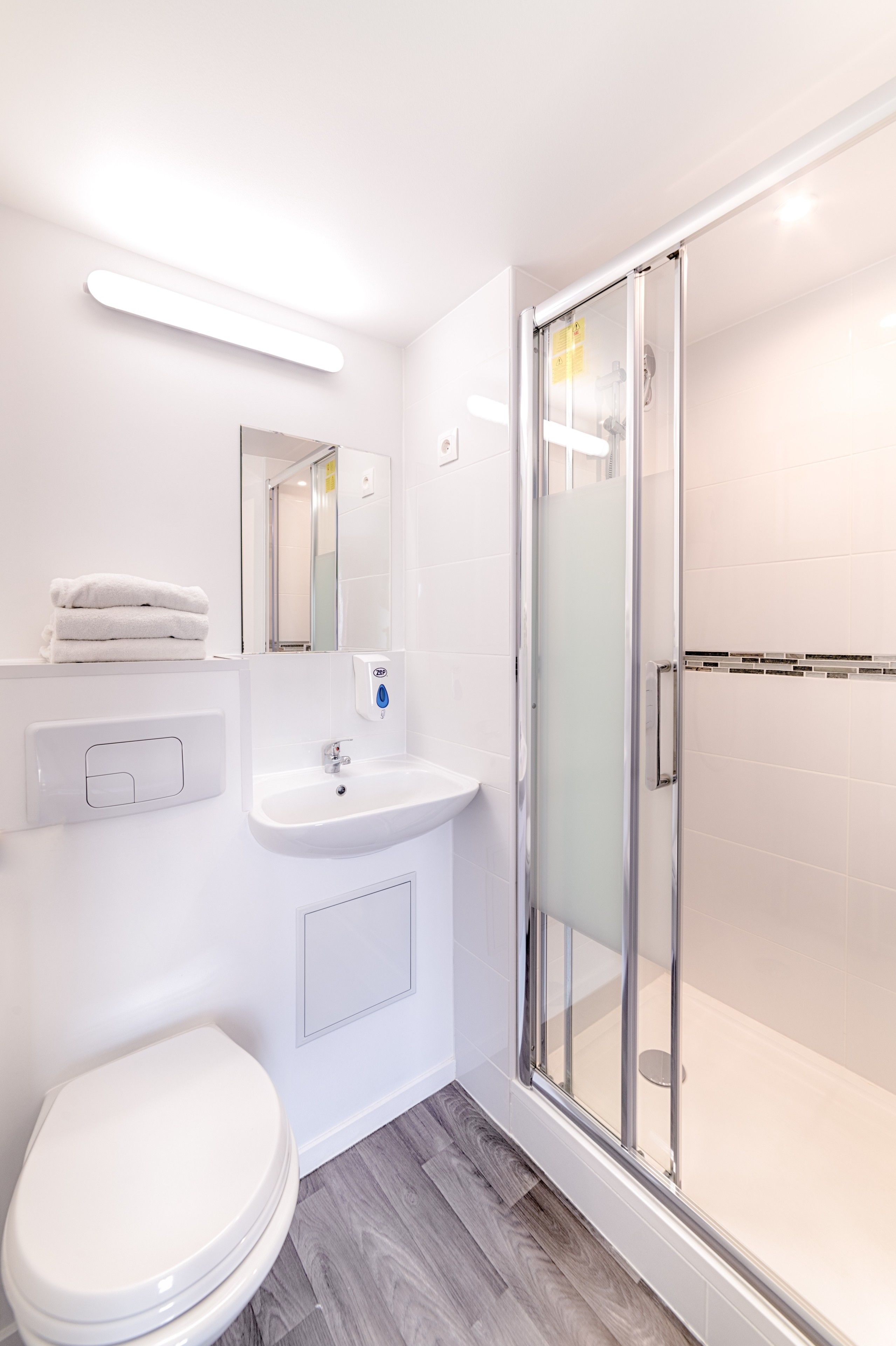 A modern bathroom with a toilet, sink, and glass-enclosed shower.