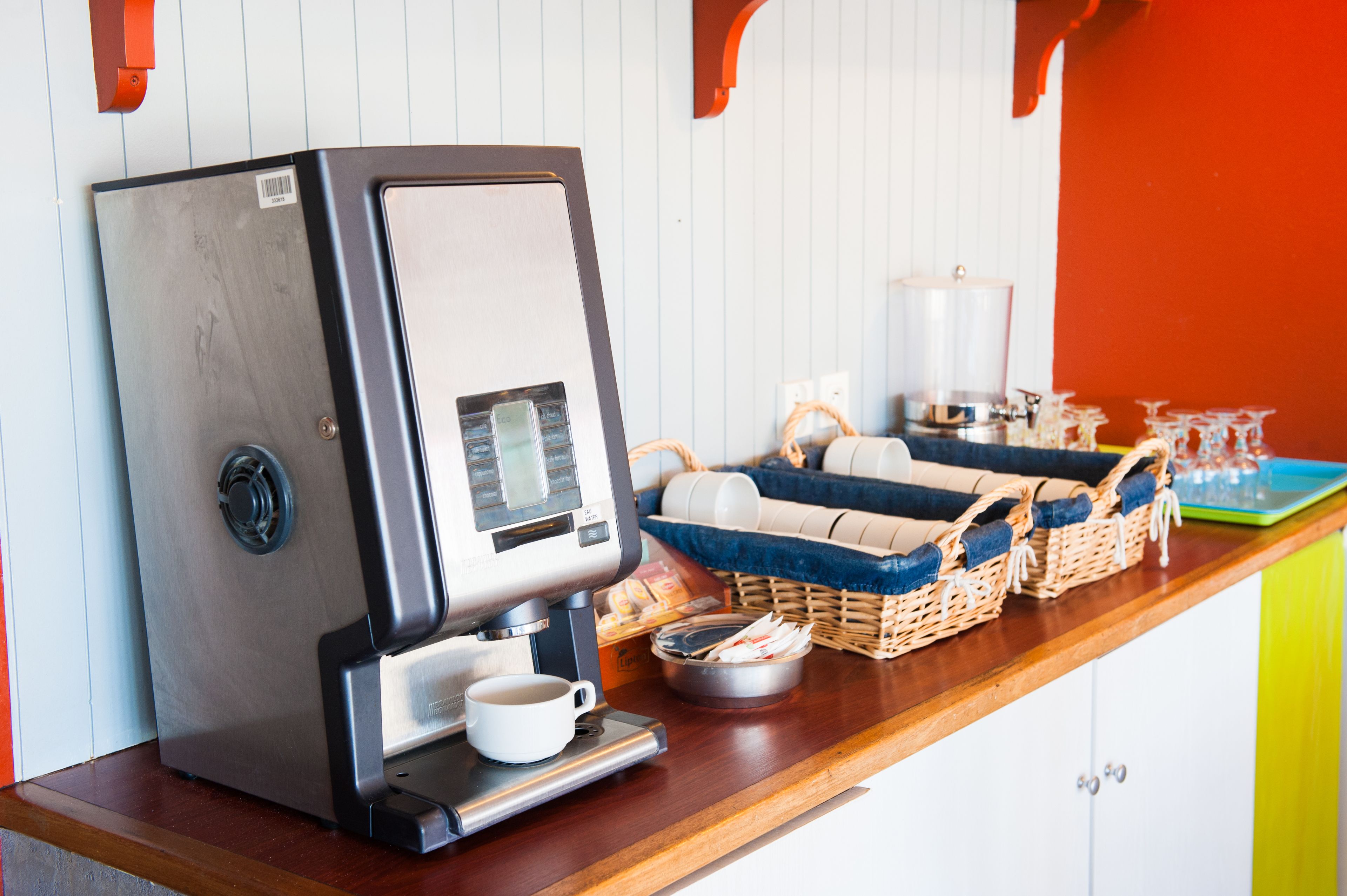 Eine Kaffeemaschine, Körbe und eine Tasse auf einer Holzauslage.
