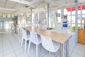 Enjoy meals in a stylish dining area with a long table and comfortable chairs, surrounded by artwork and large windows.