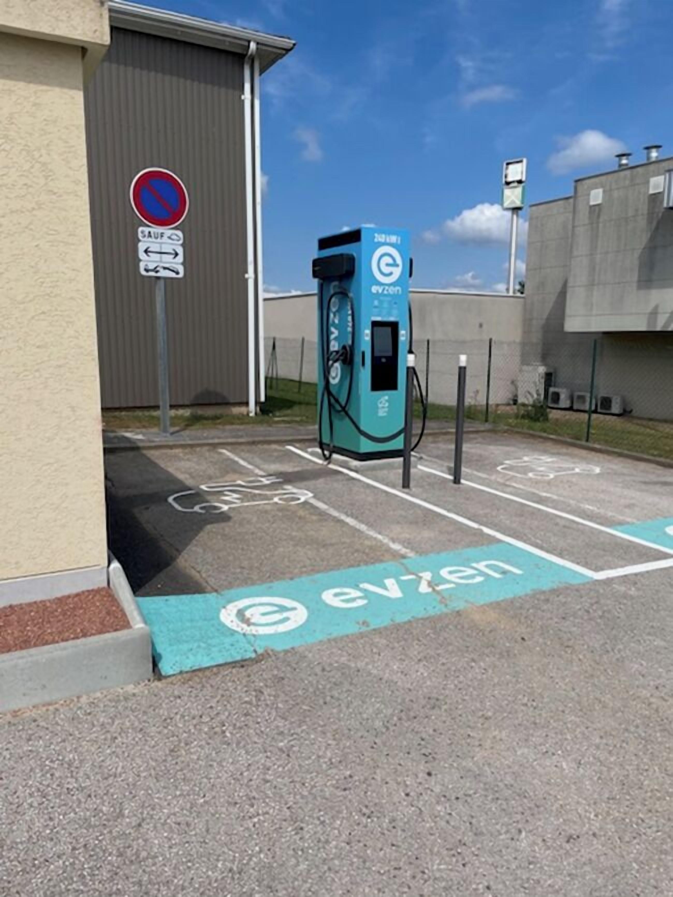 Una estación de carga para vehículos eléctricos con la marca 'evzen', y un espacio de estacionamiento reservado para la carga de vehículos eléctricos.