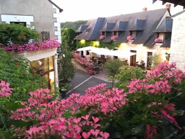 A courtyard with a stone building, a covered seating area, and pink flowering plants.