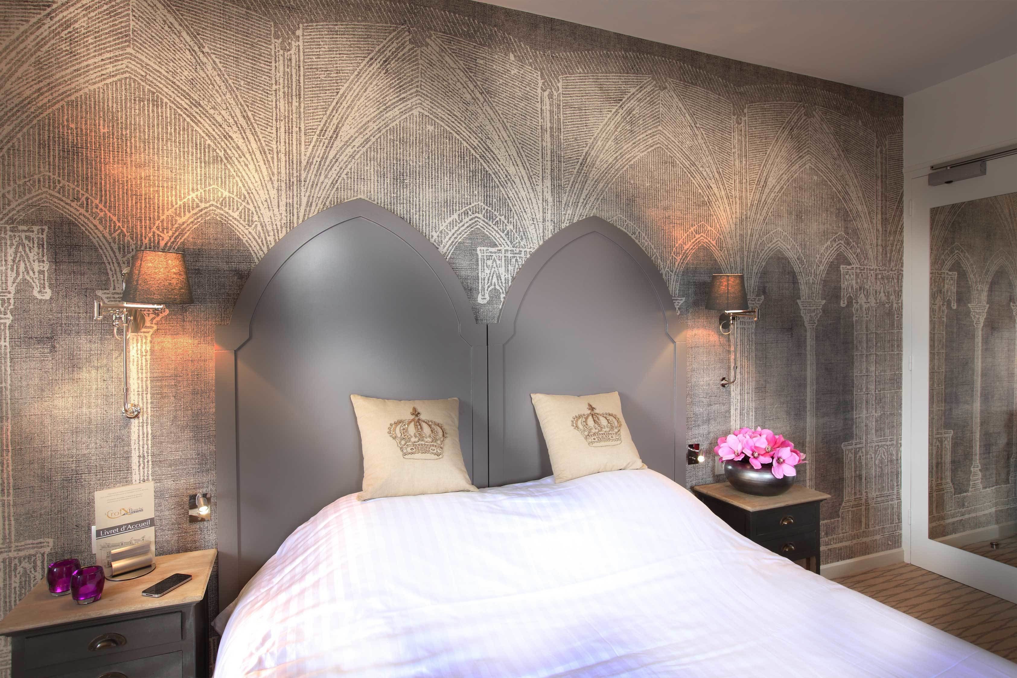 A bedroom with a large bed, two nightstands, a mirror, and a textured wall.