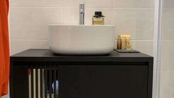 A modern bathroom with a white sink, a mirror above it, and a black cabinet below.