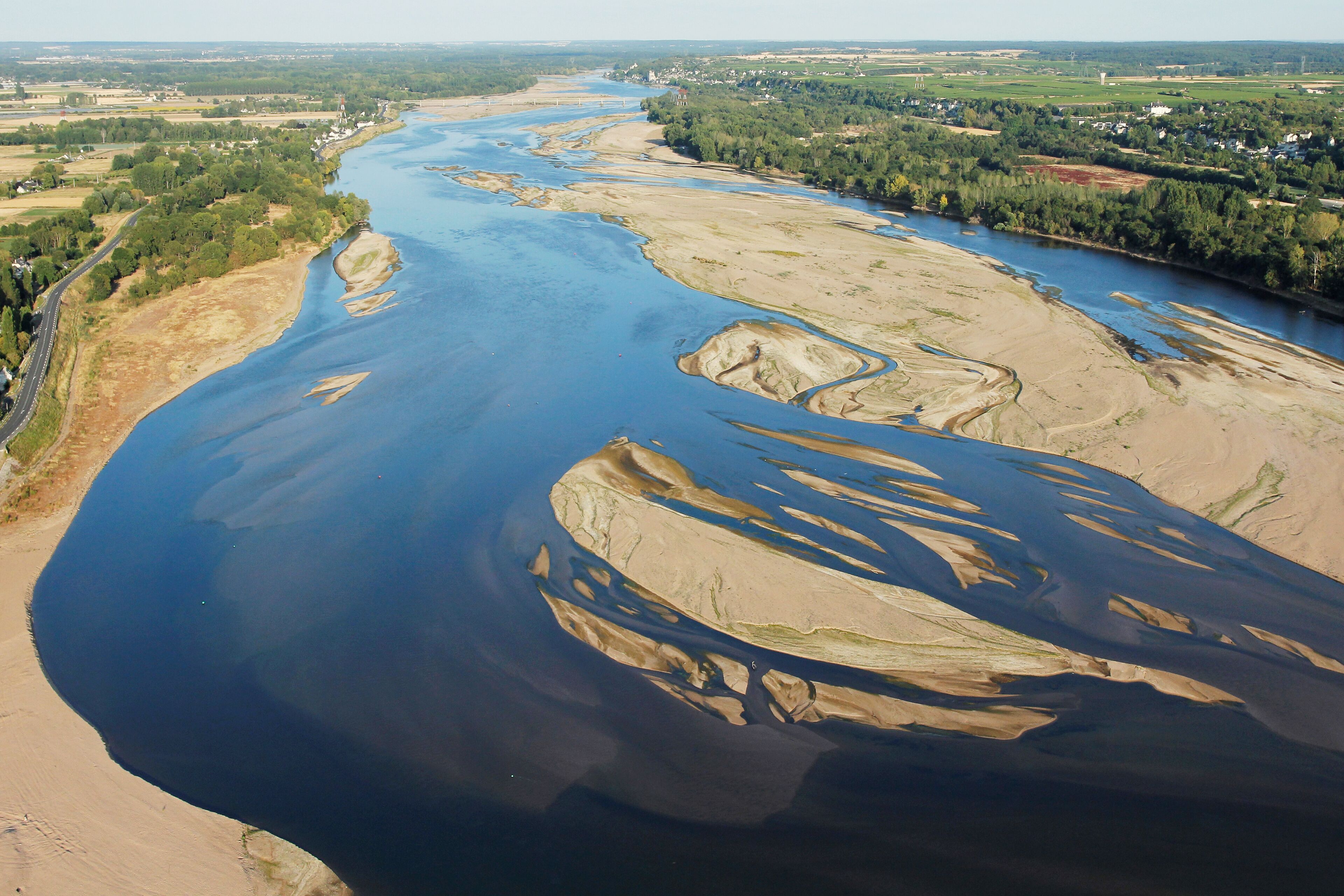 Vista aérea de un río con tierras circundantes, incluyendo una carretera y algunos edificios.