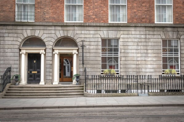 A building with a stone facade, large windows, and a black iron fence.