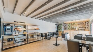 A spacious cafe with wooden flooring, metal beams on the ceiling, and a variety of seating arrangements including tables and chairs. - Logis Hôtel Restaurant Cap Hôtel. (Noyelles-Godault)