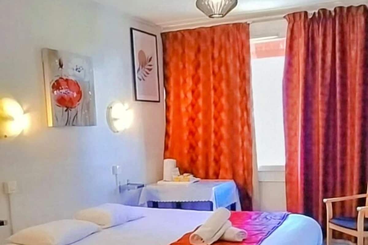 Ein Hotelzimmer mit Bett, Schreibtisch, Stuhl und einem Fenster mit Vorhängen.
