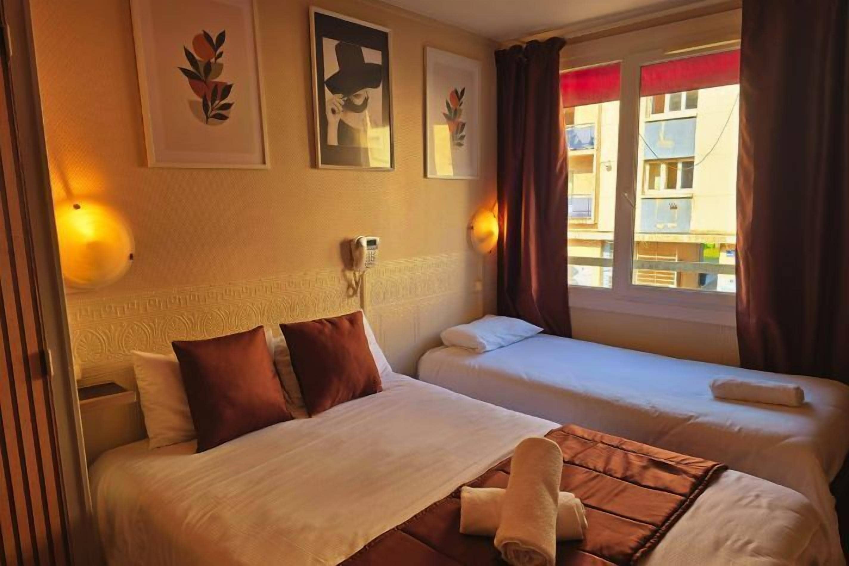 A hotel room with two beds, a headboard, wall-mounted phone, and artwork.