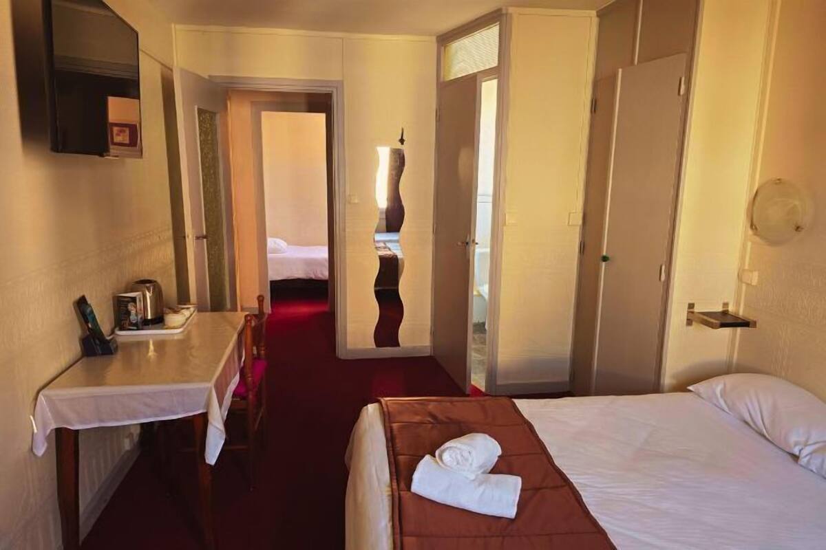 Ein Hotelzimmer mit Bett, Schreibtisch, Stuhl und einem durchgegangenen Tür sichtbaren Badezimmer.