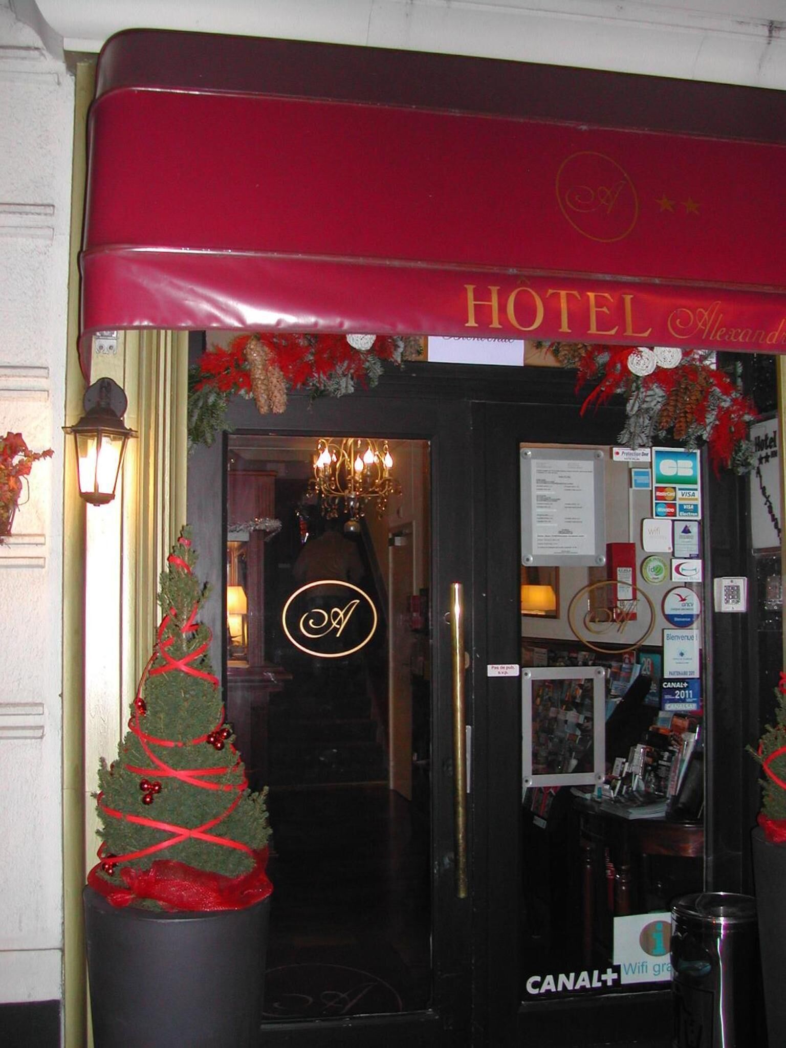A hotel entrance with a red awning, a Christmas tree decoration, and a sign indicating Canal+ availability.