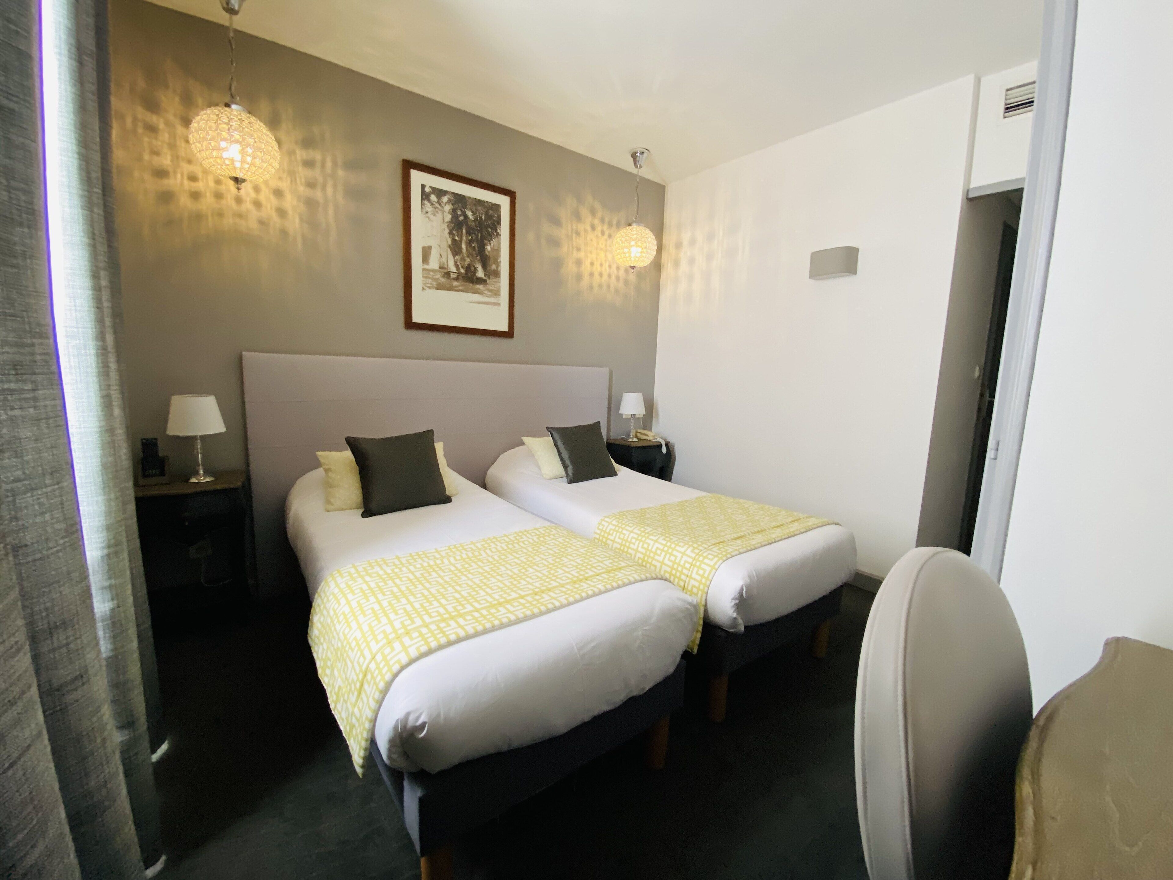 Een hotelkamer met twee bedden, een lijst aan de muur en een stoel.