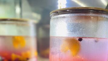 A beverage dispenser with a clear glass container filled with a colorful drink and fruit pieces.