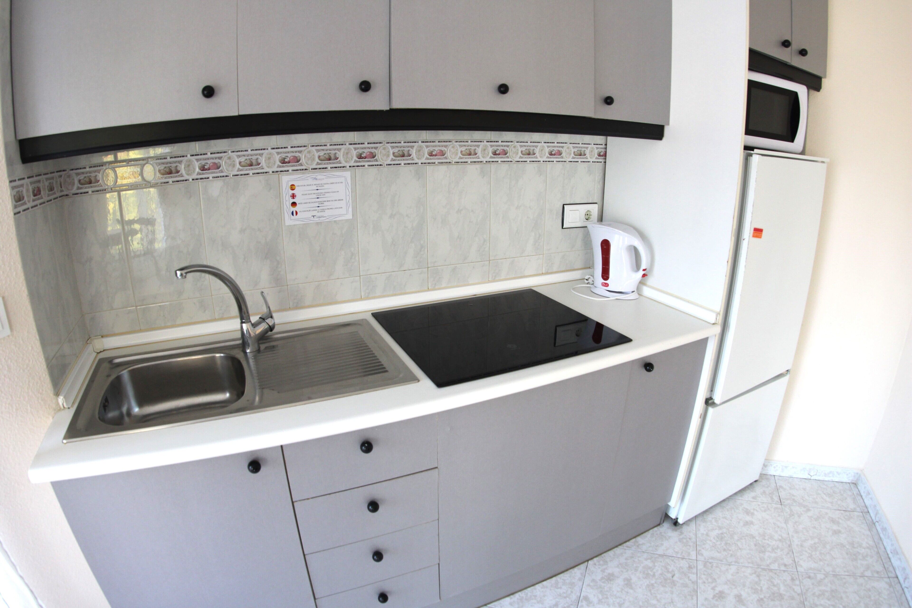 A compact kitchen with a sink, stove, and refrigerator.