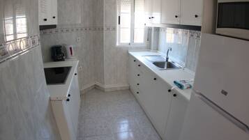 Una cocina con armarios blancos, un lavamanos y un microondas.