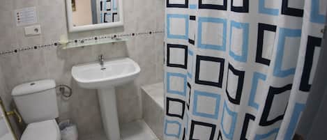 Un baño con inodoro, lavamanos y cortina de ducha.