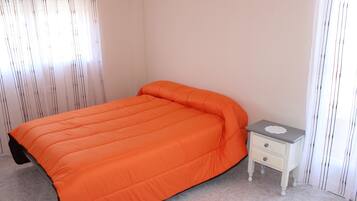 A bedroom with a single bed, a nightstand, and a window with curtains.