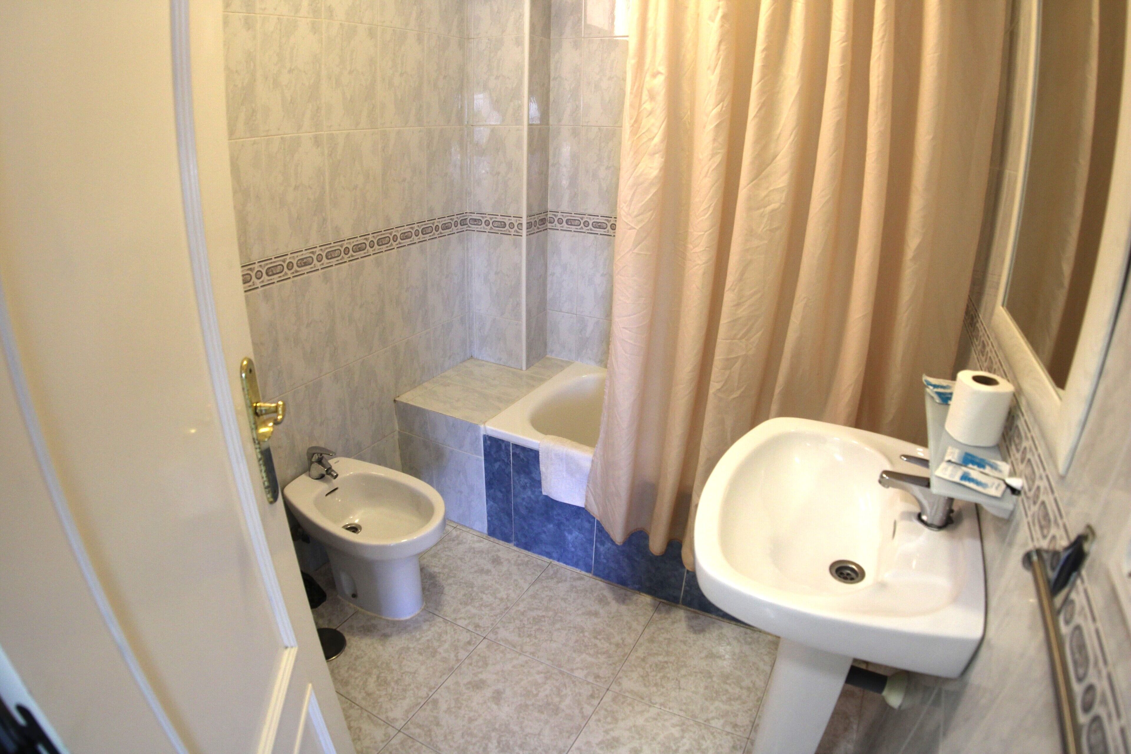 A bathroom with a bidet, a bathtub, and a sink.