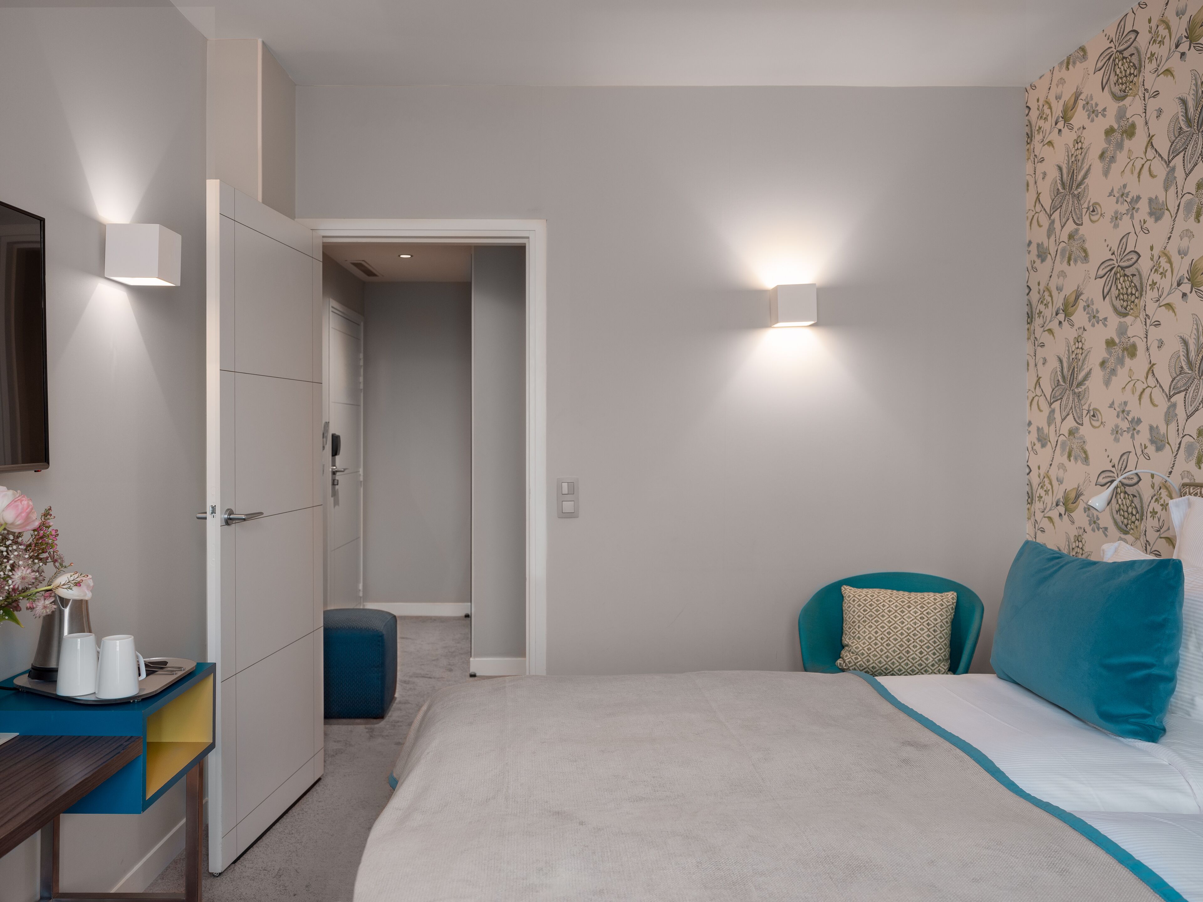 A bedroom with a bed, bedside tables, a wardrobe, and a door leading to another room.