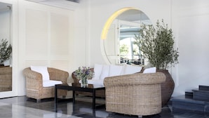 A modern lobby with wicker furniture, a large mirror, and a potted plant.