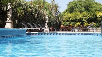 Een binnenzwembad, een buitenzwembad, ligstoelen bij het zwembad