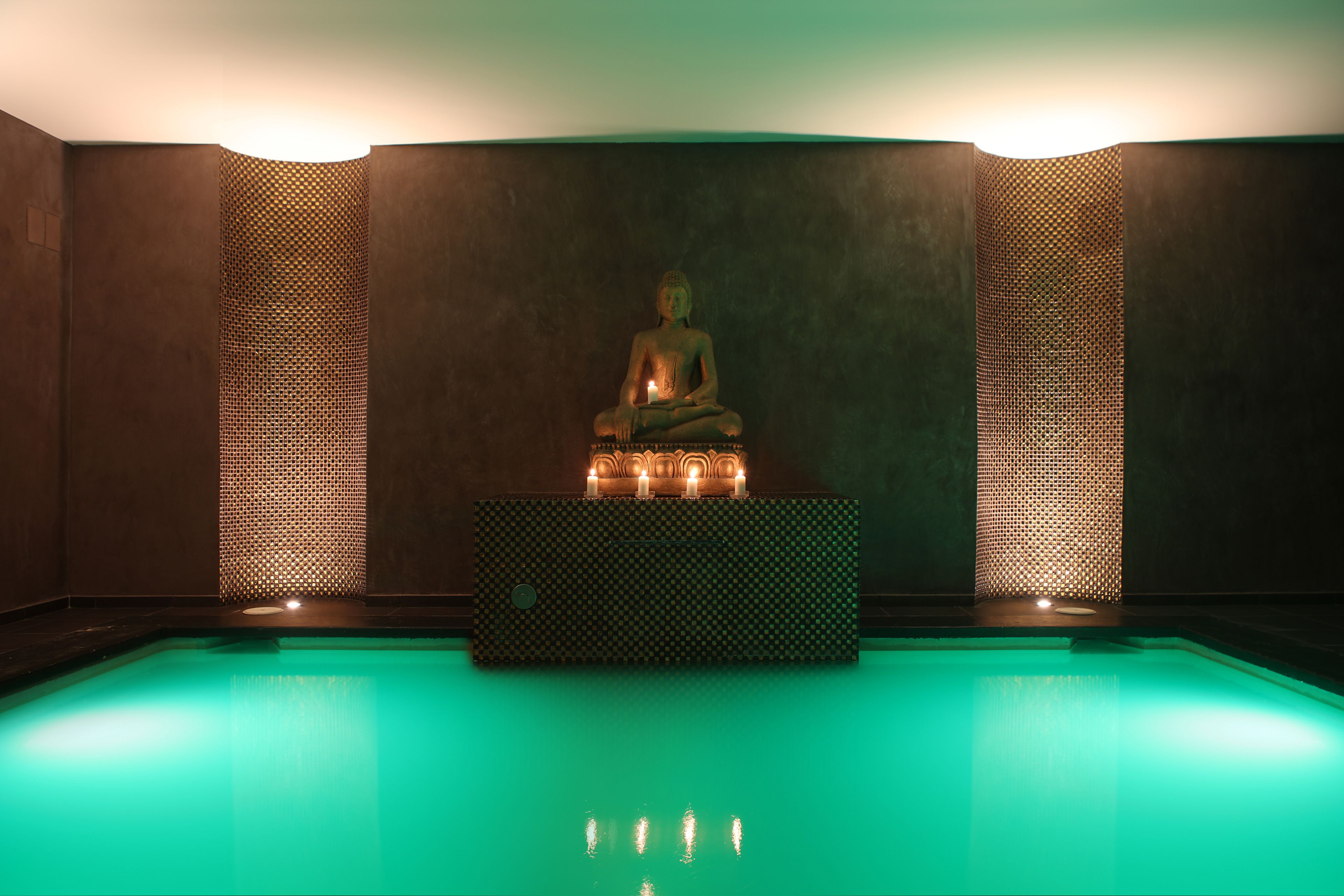 Un espacio para la meditación con una estatua, un pequeño altar y una piscina.