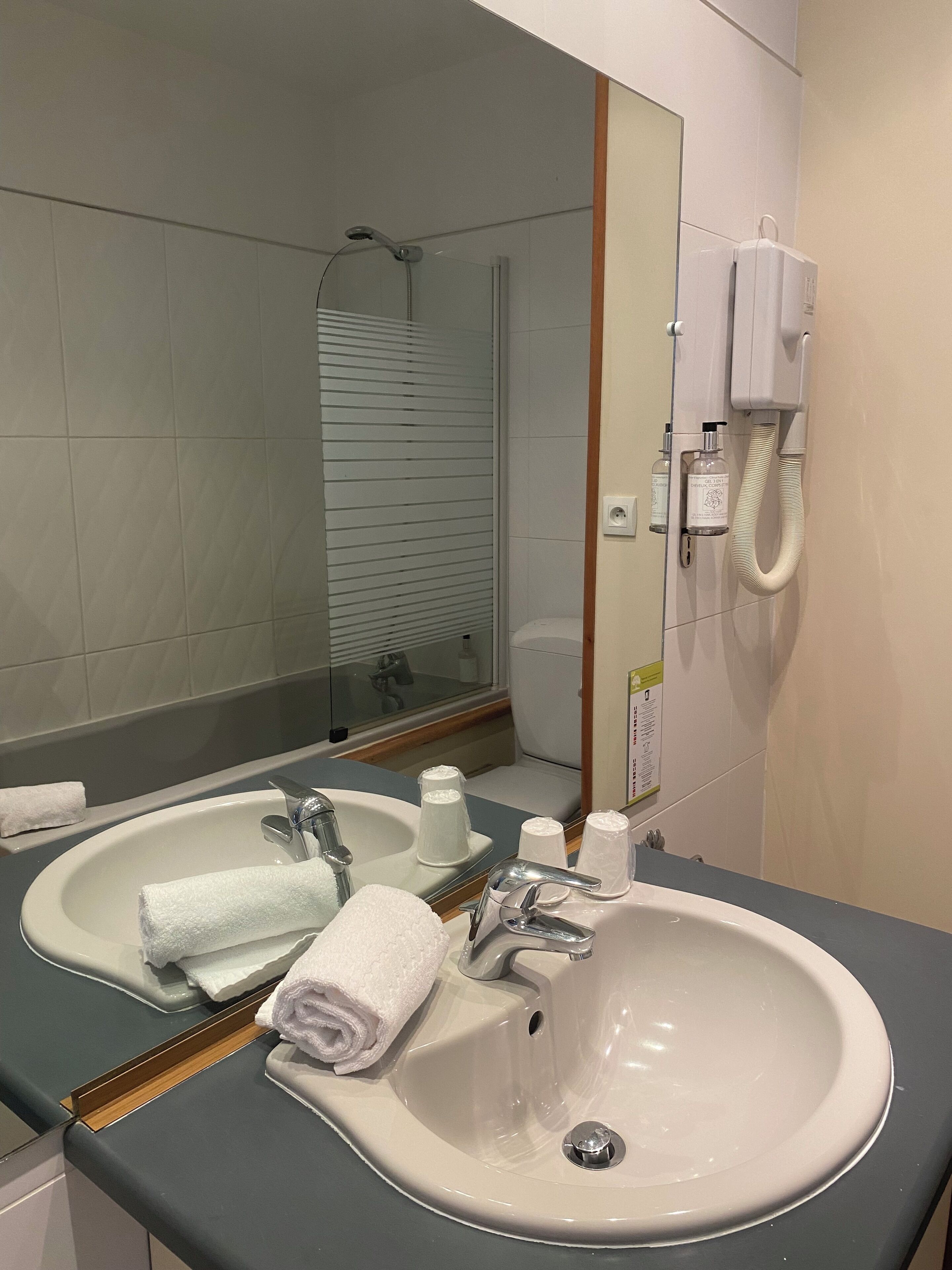 Un baño con dos lavamanos, un espejo, ducha y secador de pelo.