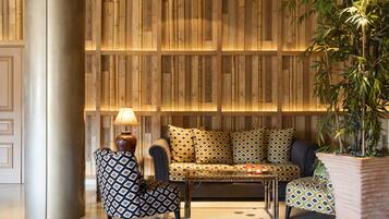 A modern living room with a sofa, patterned cushions, a coffee table, a lamp, and a potted plant.