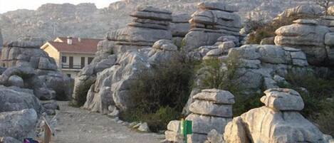 A rocky landscape with a path leading to a building with a red roof.
