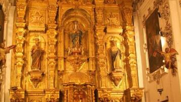 Interior de una iglesia con altares dorados ornamentados y una congregación sentada.