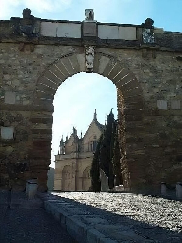 An arched stone bridge leading to a historic building with pointed towers and a central entrance. - Hostal Colón (Antequera)
