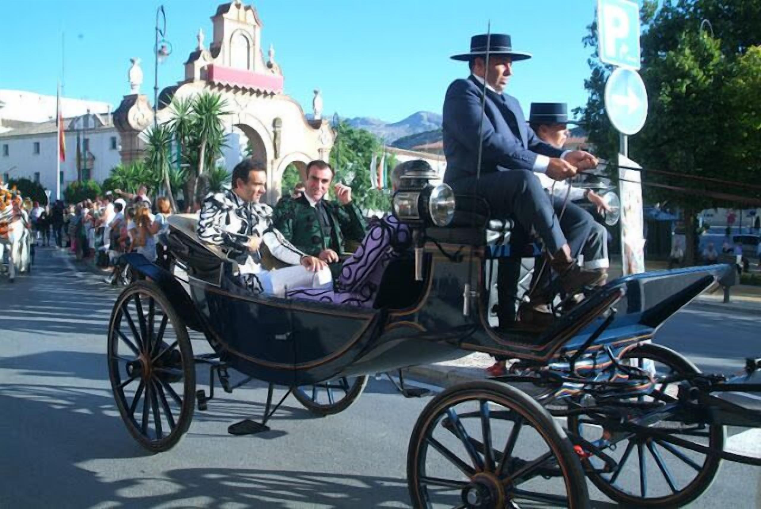 A horse-drawn carriage with passengers, a vintage camera, and a building with a pink roof in the background.