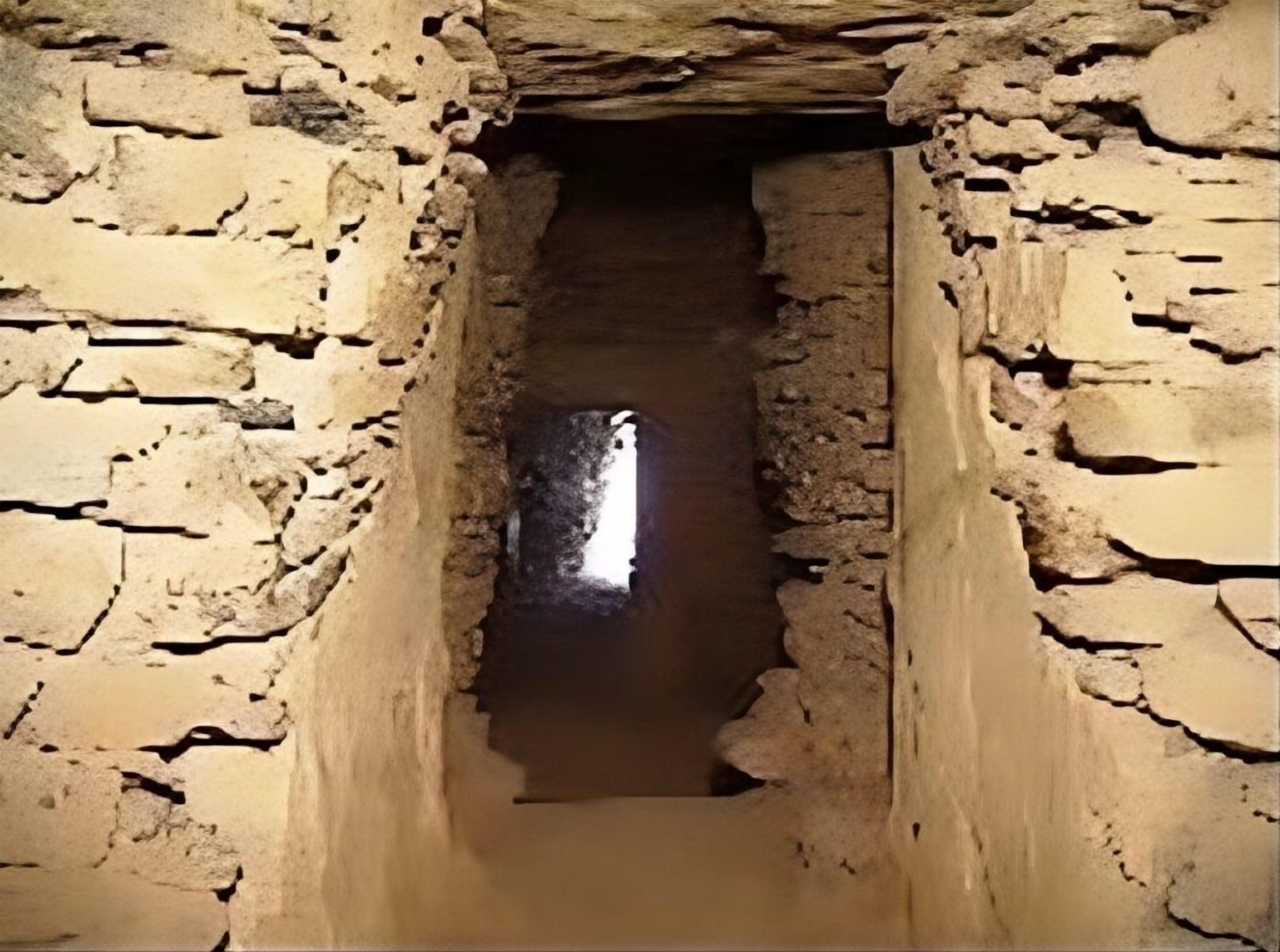 Un estrecho pasaje de piedra, con paredes de textura rugosa y piedras de formas irregulares.
