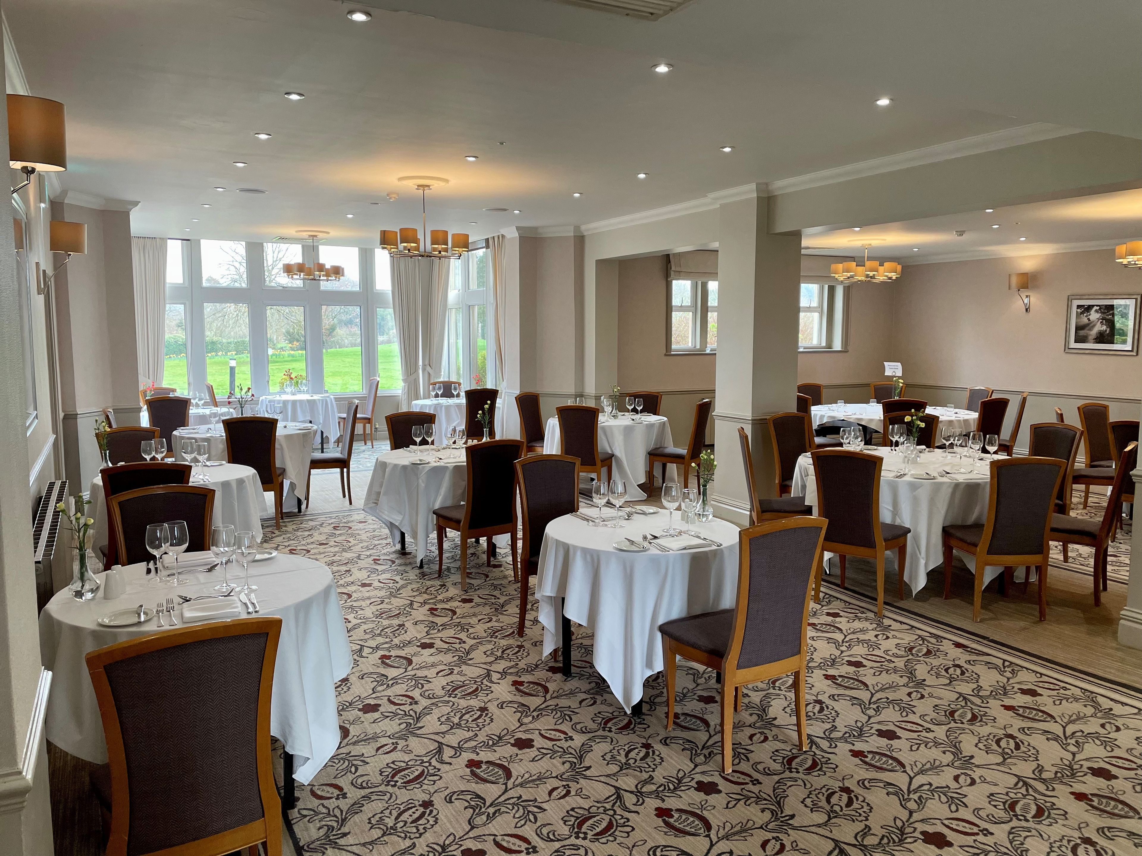 A dining area with round tables, chairs, and a patterned carpet.
