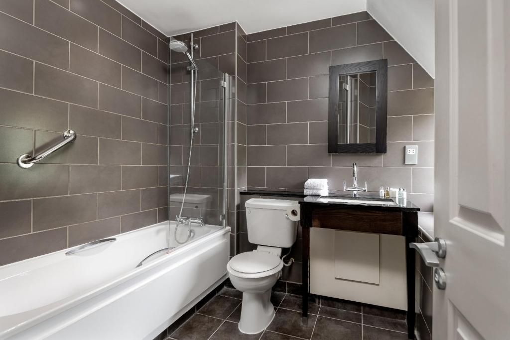 A modern bathroom with a bathtub, toilet, and shower area.