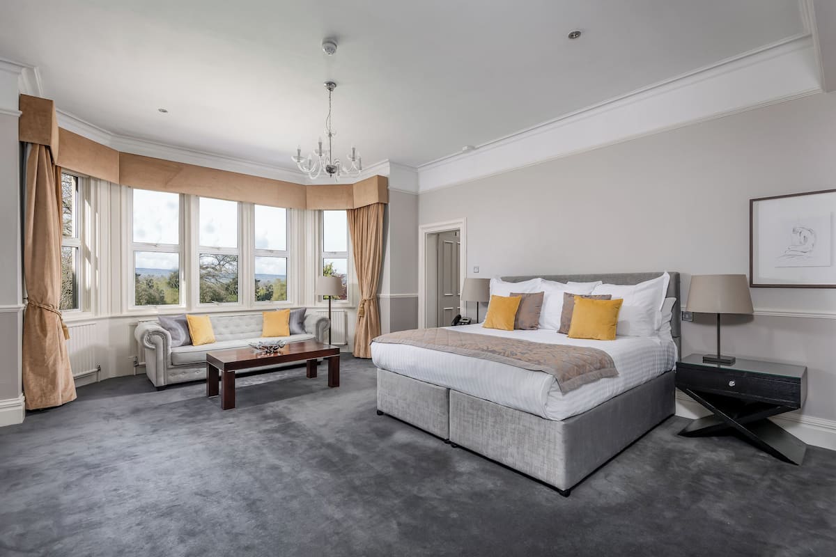 A bedroom with a large bed, a sofa, a coffee table, and a nightstand.