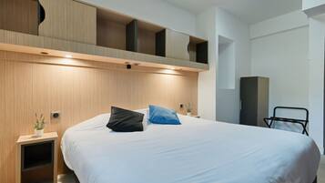 Une chambre moderne avec un grand lit, une tête de lit en bois, des tables de chevet et une étagère intégrée au-dessus du lit.